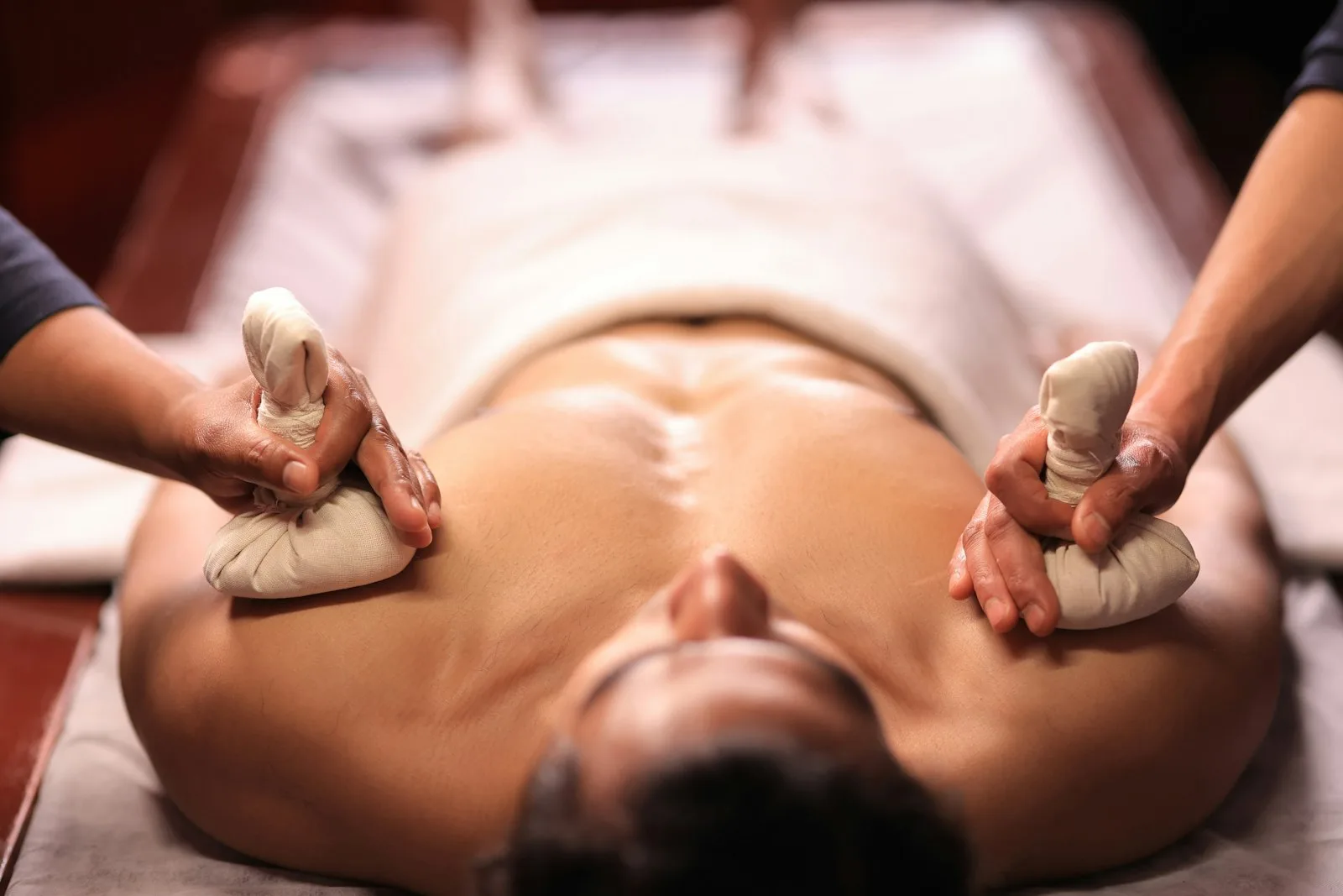 Masaje con pindas herbales calientes aplicadas sobre la espalda en un spa